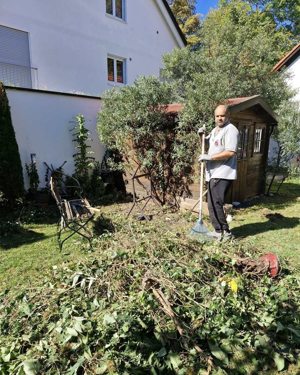Großer Haufen Grünschnitt im Garten, dahinter Aofok Nukhailawi mit Rechen