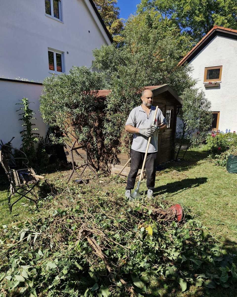 Aofok Nukhailawi mit Rechen neben aufgeschichtetem Grünschnitt