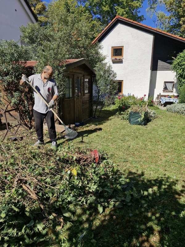 Gartenarbeit an einem sonnigen Tag mit Grünschnitt im Vordergrund