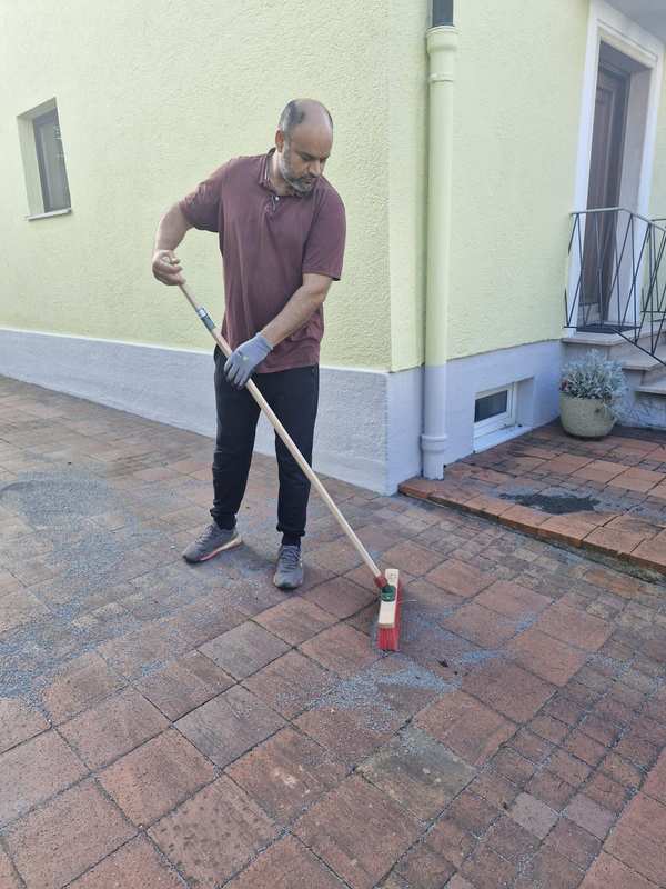Kehren einer Pflasterfläche vor dem Haus