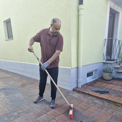 Kehren einer Pflasterfläche vor dem Haus